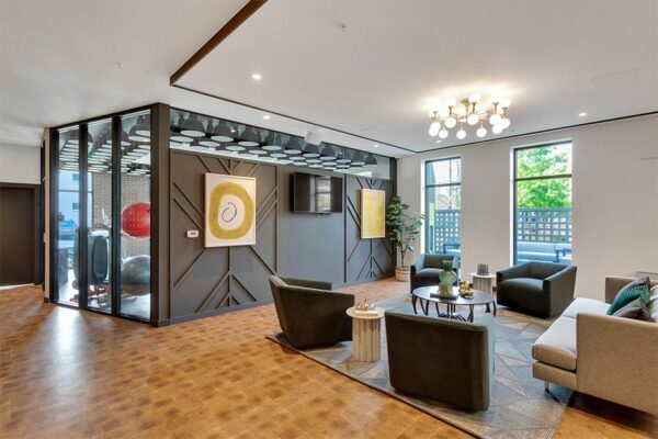 Lounge with end grain wood floor, plush seating, modern lighting fixture, and large windows.