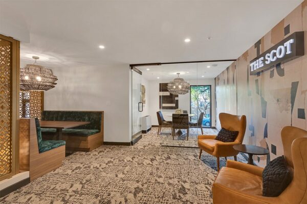 Lounge with plush booth, leather wingback chairs, decorative wallpaper, and The Scot lighted sign.