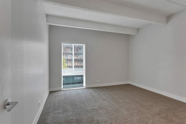 Bedroom with carpet, grey walls, white trim, and large window.