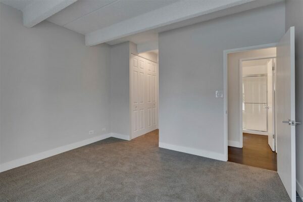 Bedroom with carpet, grey walls, white trim, and large closet doors.
