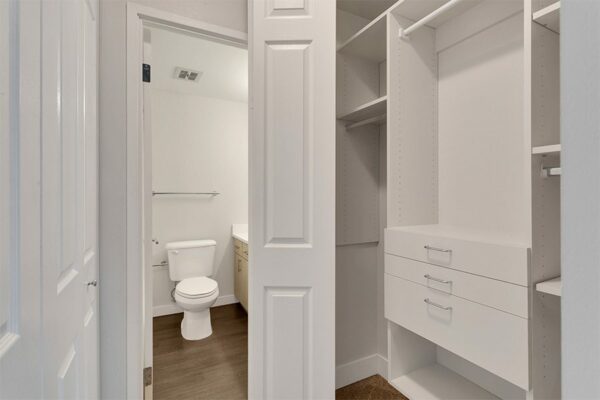 Closet with large built in shelves and drawers and door to bathroom.