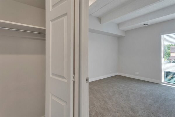 Closet with grey walls, built in shelves, and door to bedroom.