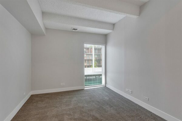 Bedroom with carpet, grey walls, white trim, and large window.