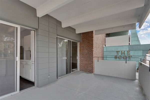 Balcony with concrete railings and doors to living room and kitchen overlooking The Scot building sign.