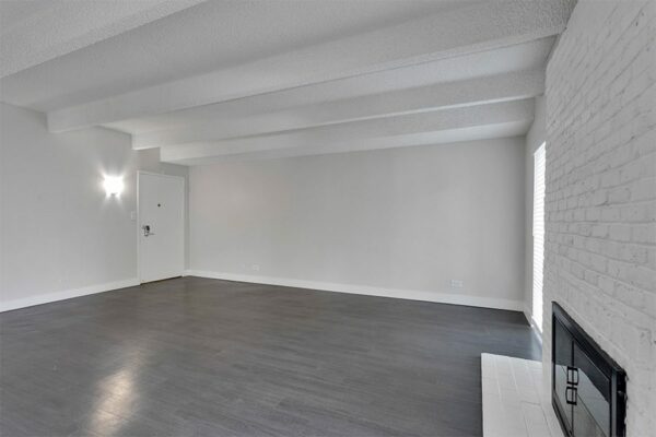 Living room with wood floor, grey walls, and white brick accent wall with fireplace.
