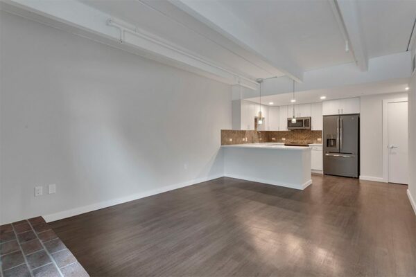Living area with wood floors, grey walls, white trim, and updated kitchen.