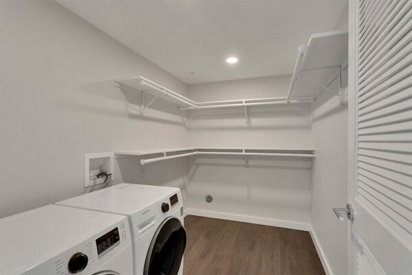 Walk in closet with built in shelves and washer and dryer.
