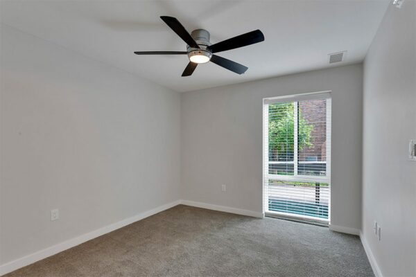 Bedroom with carpet, grey walls, white trim, ceiling fan, and large window.