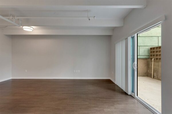 Living room with wood floor, grey walls, white trim, and door to balcony.