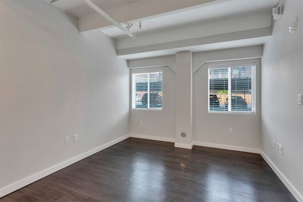Living room with wood floor, grey walls, white trim, and large windows.