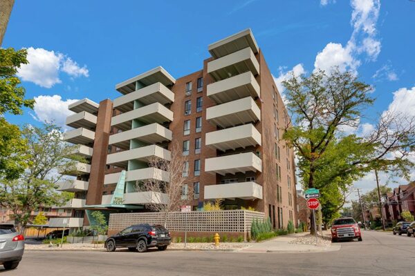 The Scot apartments with classic brick construction, large balconies, mature trees, and street parking.