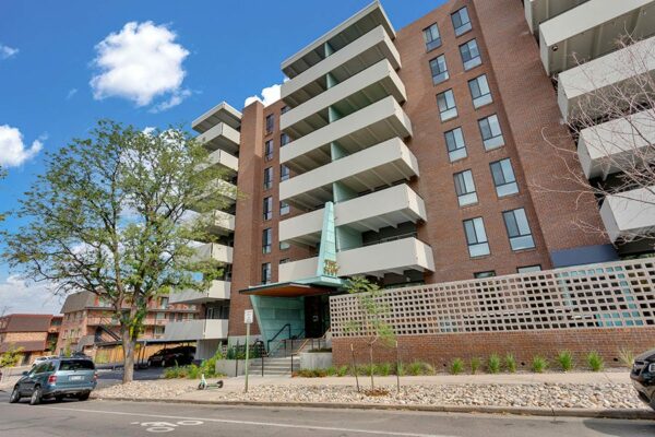 The Scot apartments with classic brick construction, large balconies, mature trees, and street parking.