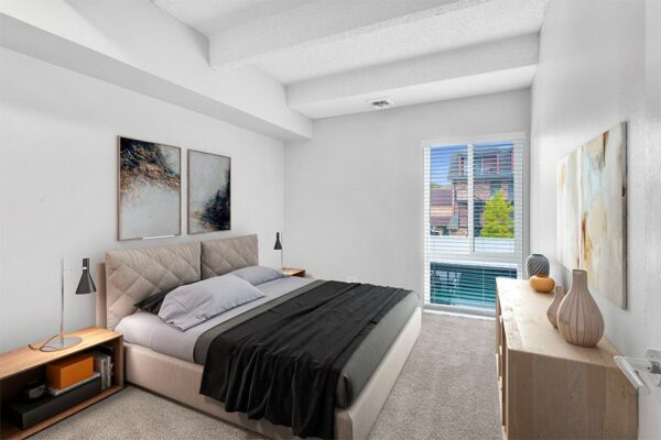 Bedroom with carpet, platform bed with plush headboard, modern furniture, and large window.