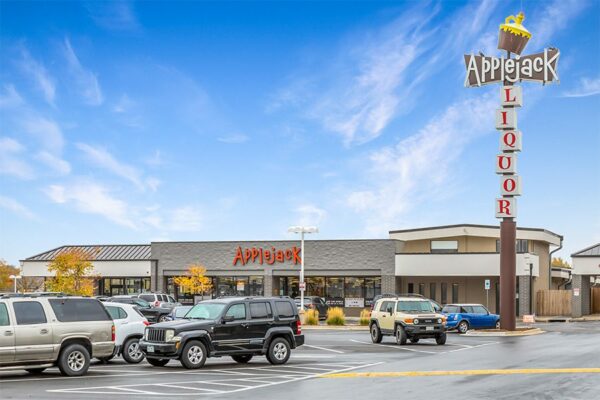 Applejack Liquors store front with parked cars and large retro signage.