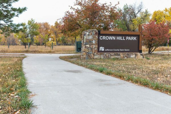 Crown Hill Park with large monument sign, concrete paths, and tall autumnal trees.