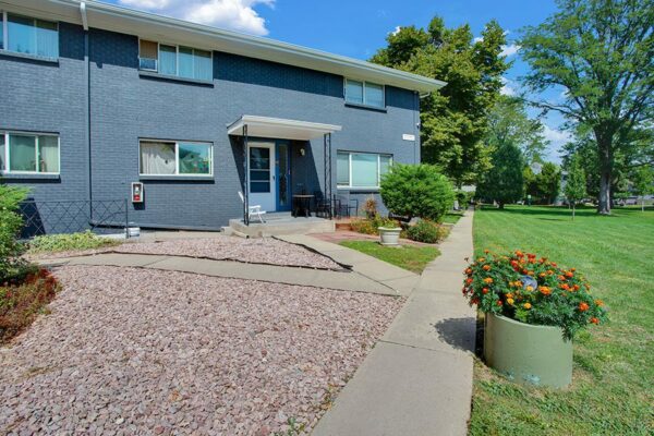 Trace Townhomes with grey brick construction, concrete pathways and patio, and lush green lawns.