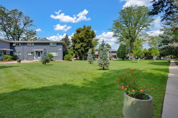 Trace Townhomes with grey brick construction, concrete pathways and patio, and lush green lawns.