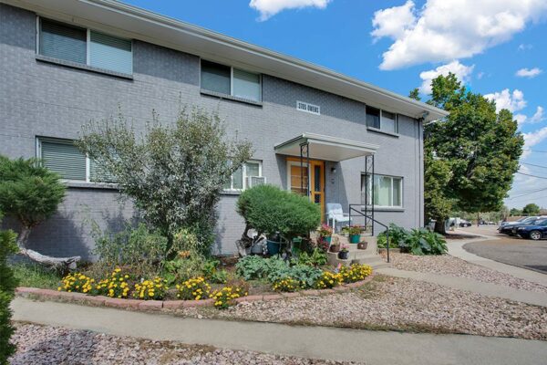 Trace Townhomes with rocky landscaping, large plants, concrete pathways, and grey brick construction.
