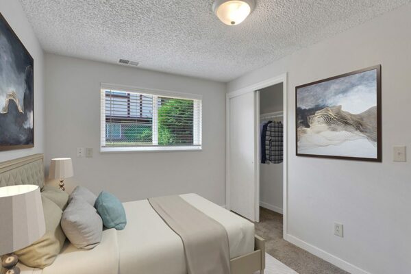Bedroom with carpet, bed with plush headboard, artwork, large closet and window.