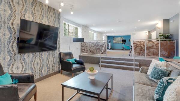 resident club room with couches, shuffle board and exercise equipment