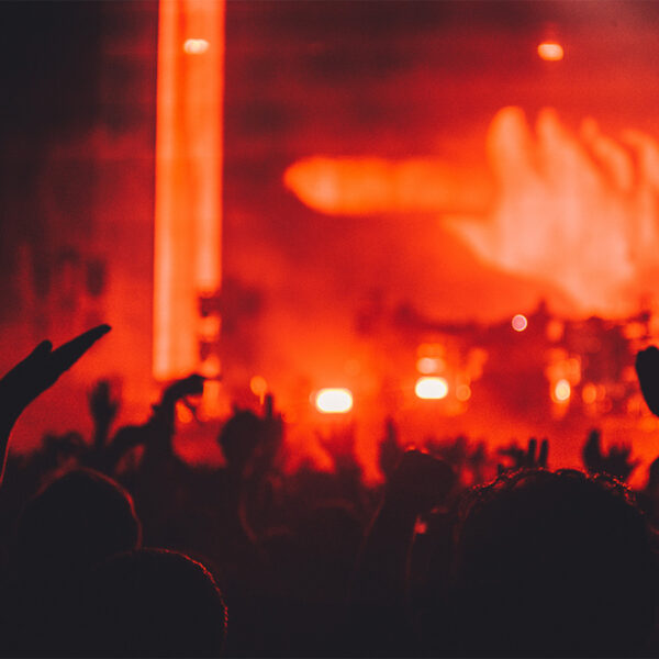 People dancing at concert with brightly lit red stage.