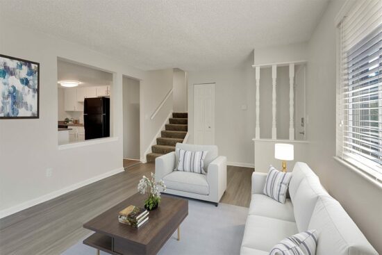 Living room with rug, couch, chairs and wall art.