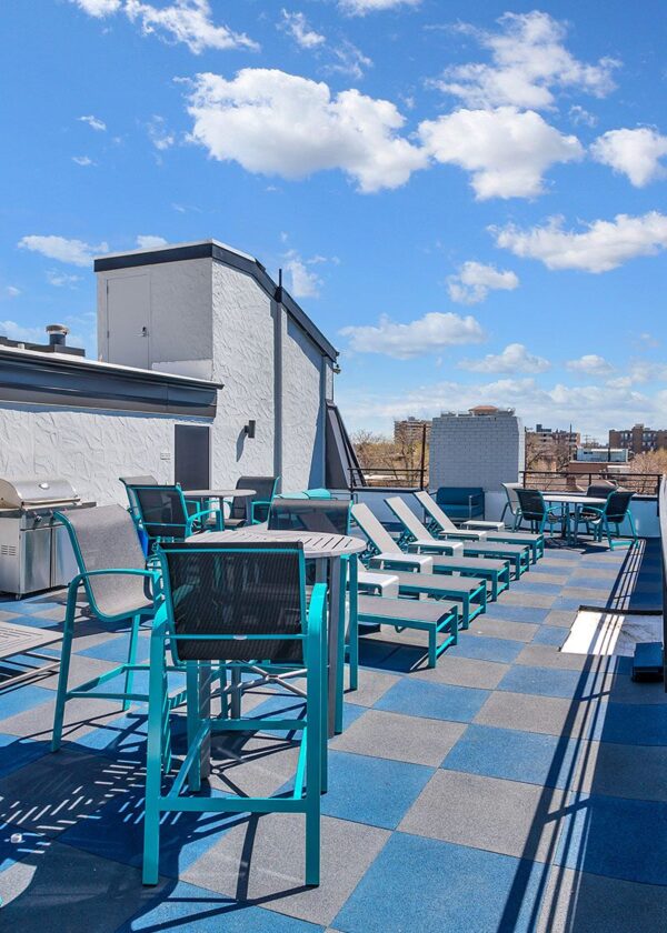 Rooftop patio with outdoor furniture, BBQ grill, and metal railing overlooking Denver.