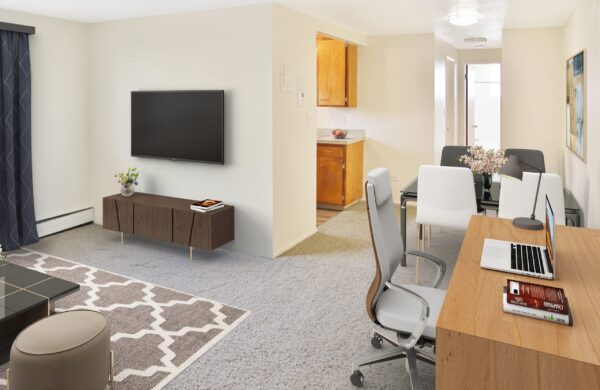 Living area with desk, dining table, and console with wall mounted TV.
