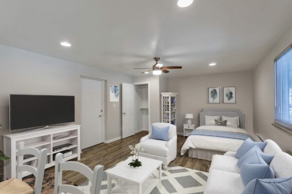 Studio living area with plush couch, dining table, bed, and closet.