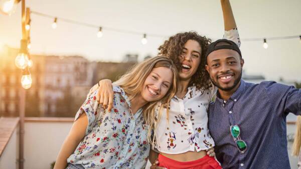 Friends smiling and posing together on rooftop patio.