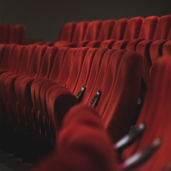 Rows of red fabric stadium seats in movie theater.