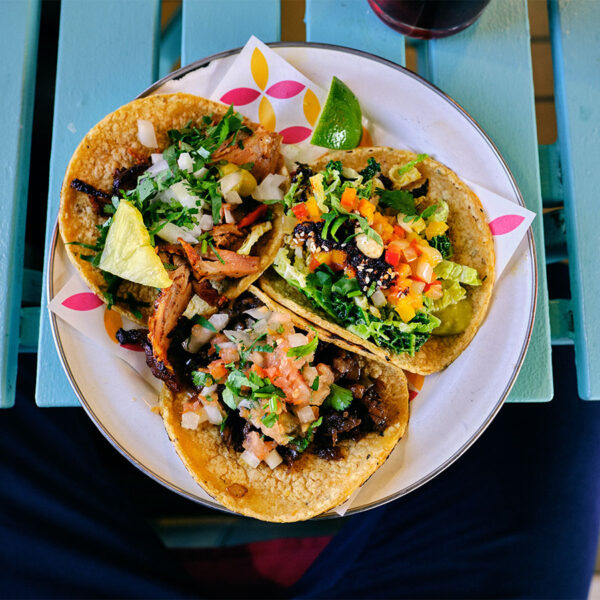 Plate of tacos with meat and vegetables on bright blue wood table.