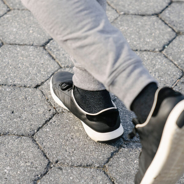 Person in grey sweatpants and black sneakers walking on hexagonal stone path.