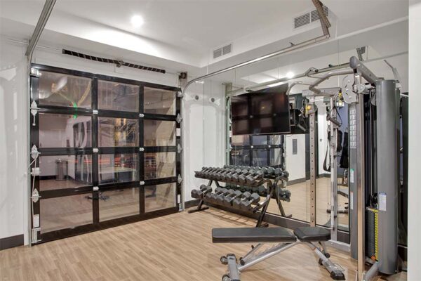 Apartment gym with free weights and a Smith machine.
