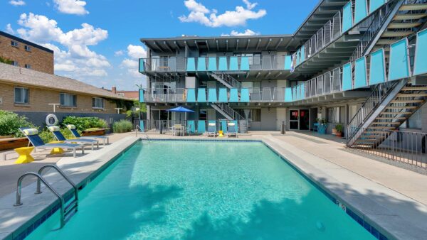 Pool area with bright blue water overlooked by apartment balconies.
