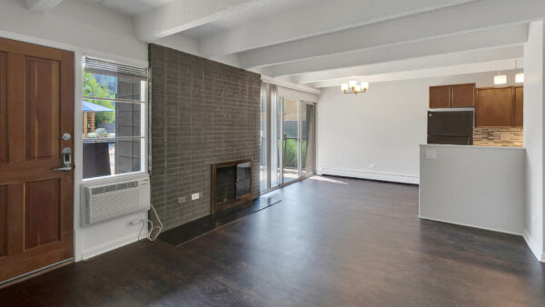 Living area with wood floor, brick accent wall with fireplace, and door to balcony.