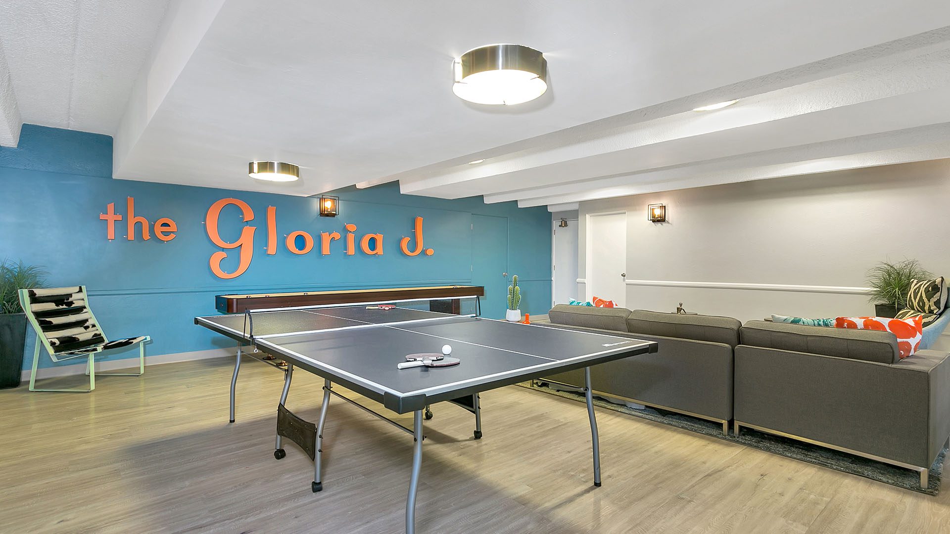 833 Dexter clubroom with wood floor, table tennis and shuffleboard, and blue accent wall with