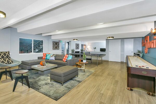 Club room with wood floor, plush seating, modern furniture, games tables, and wall art.