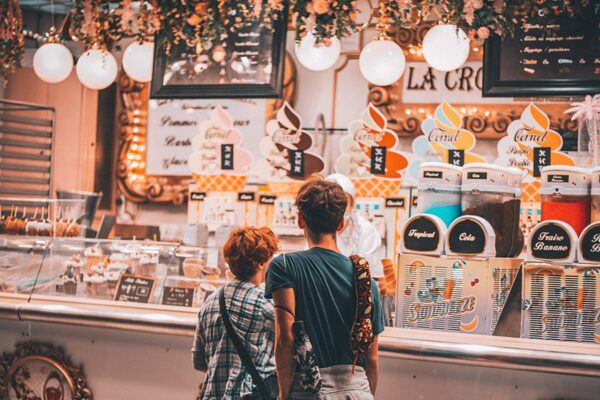 Two people in line at food truck with smoothie machines and ice cream.
