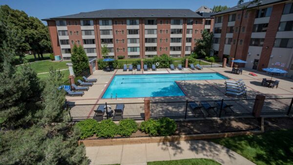 Aerial view of Colorado Station fenced pool area with lounge chairs and dining tables.