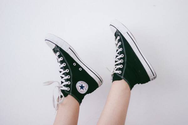 Detail of black Converse shoes in front of white wall.