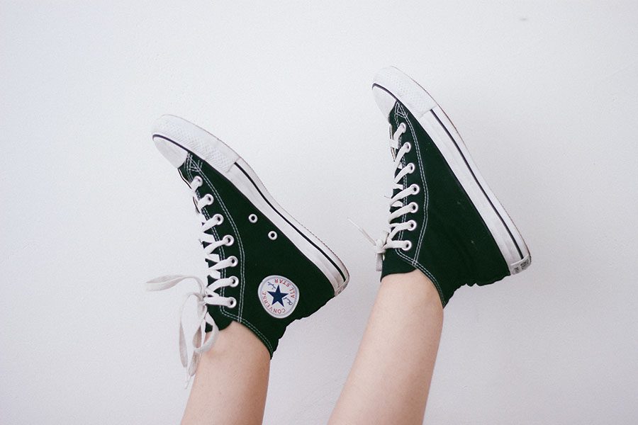 Detail of black Converse shoes in front of white wall.