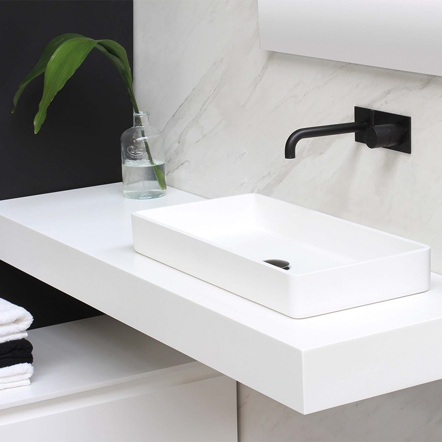 Modern sink with stone counter and jar with plant.