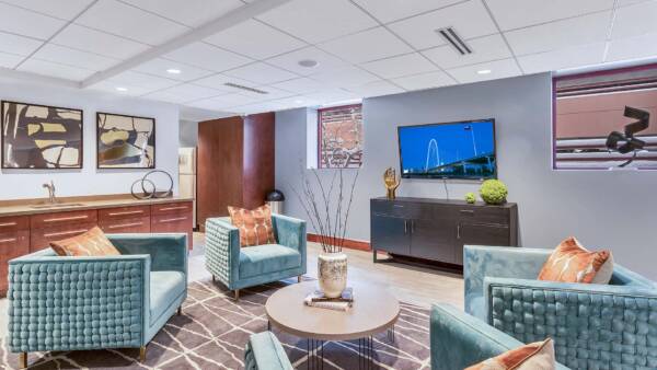Lounge with rug, plush lounge chairs, modern furniture, and wall mounted TV.
