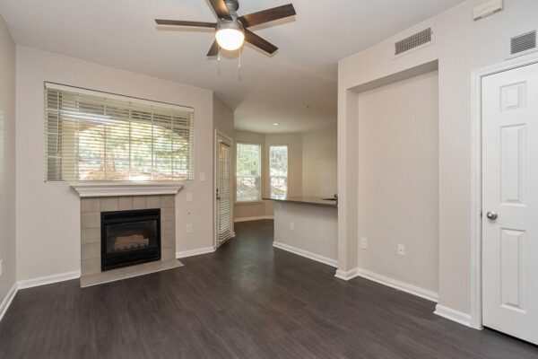 Living room with wood floor, warm grey walls, white trim, fireplace, and ceiling fan.
