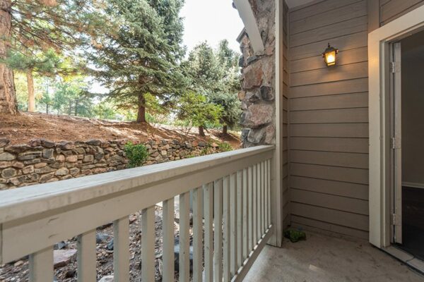 Balcony with wood railing and door to apartment overlooking rocky landscaping.