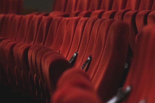 Rows of red fabric stadium seats in movie theater.