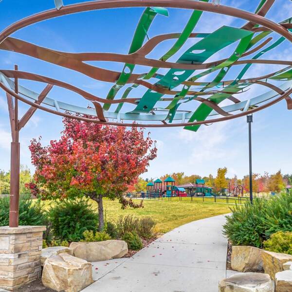 A park in Wheat Ridge with a playground, trees, and an art fixture.