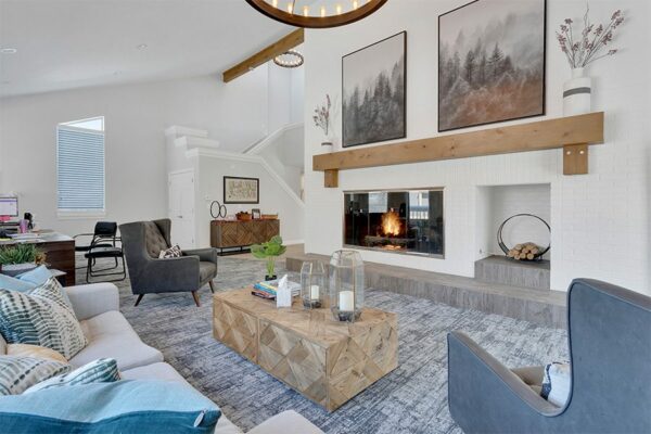 Lounge with carpet, plush furniture, large fireplace, and round chandelier.