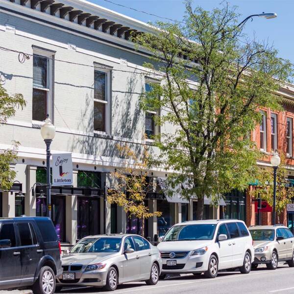 A street in downtown Littleton with shops and cars parked on the street.